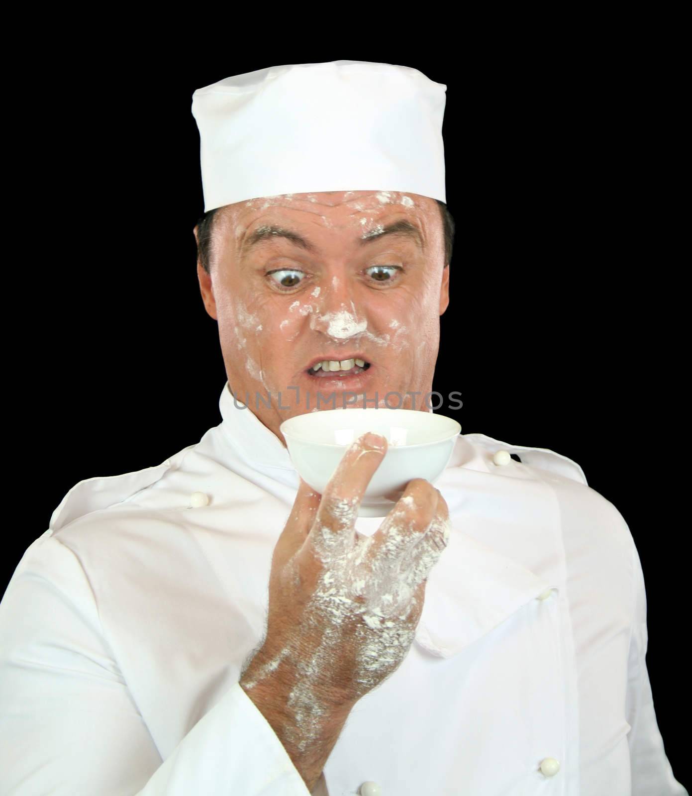 Chef is shocked when flour is blown up onto his face and hands.