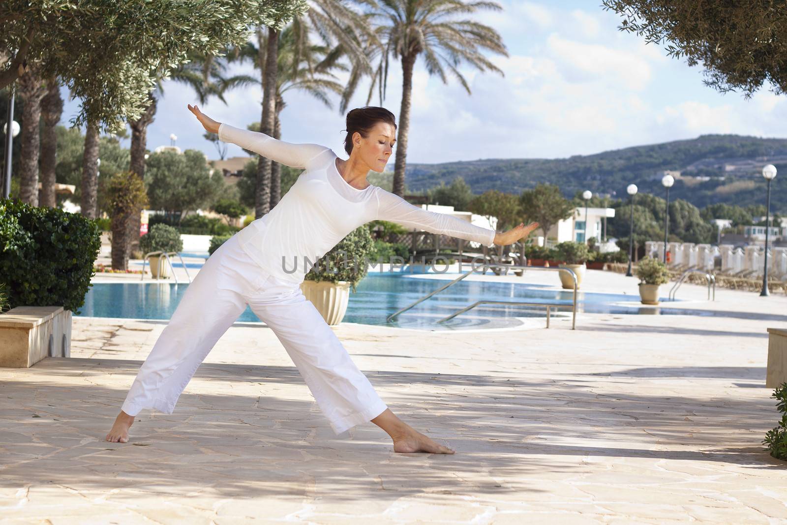 Elegant mature woman doing yoga in hotel resort