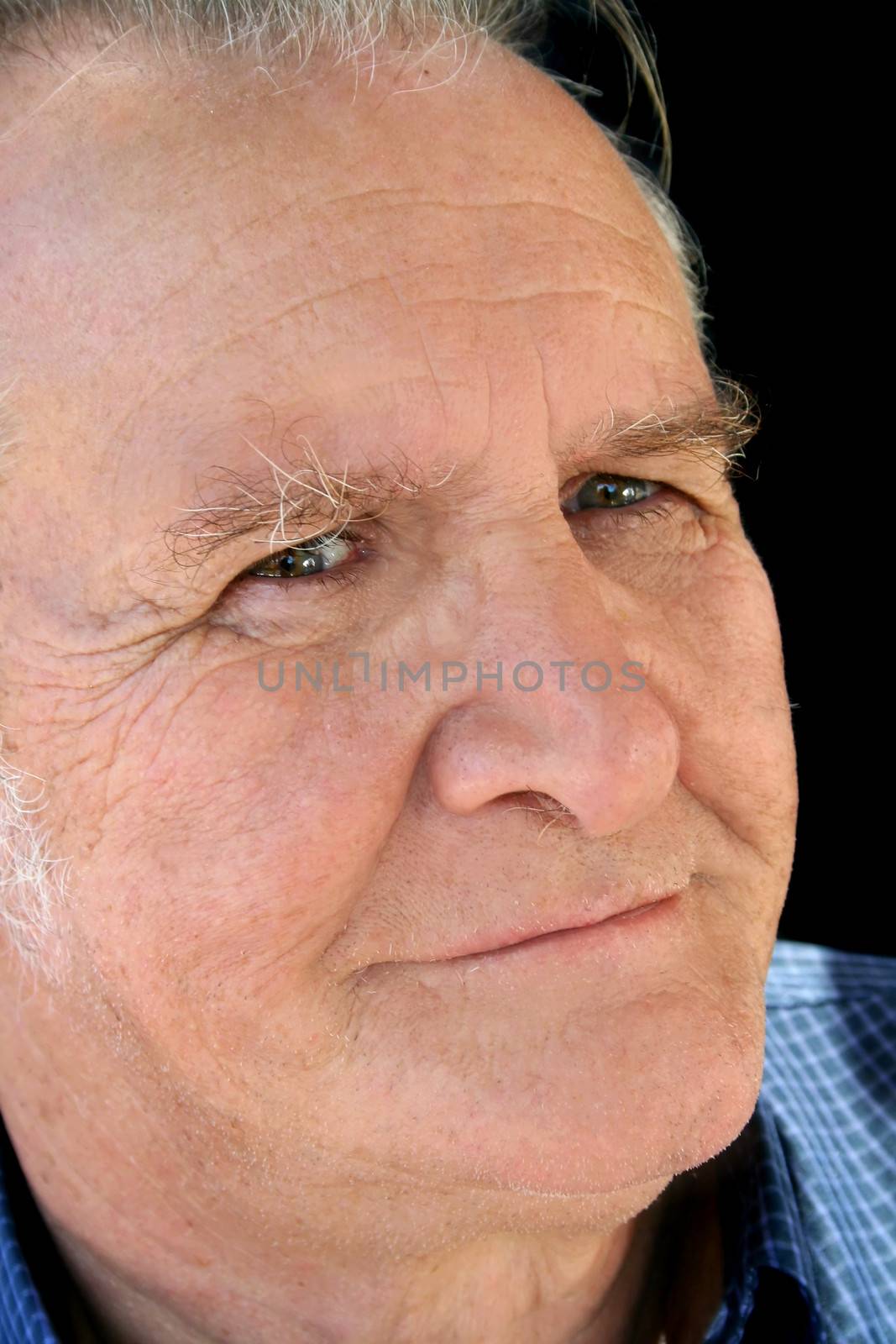 Close up of a satisfied senior male smiling looking towards camera.