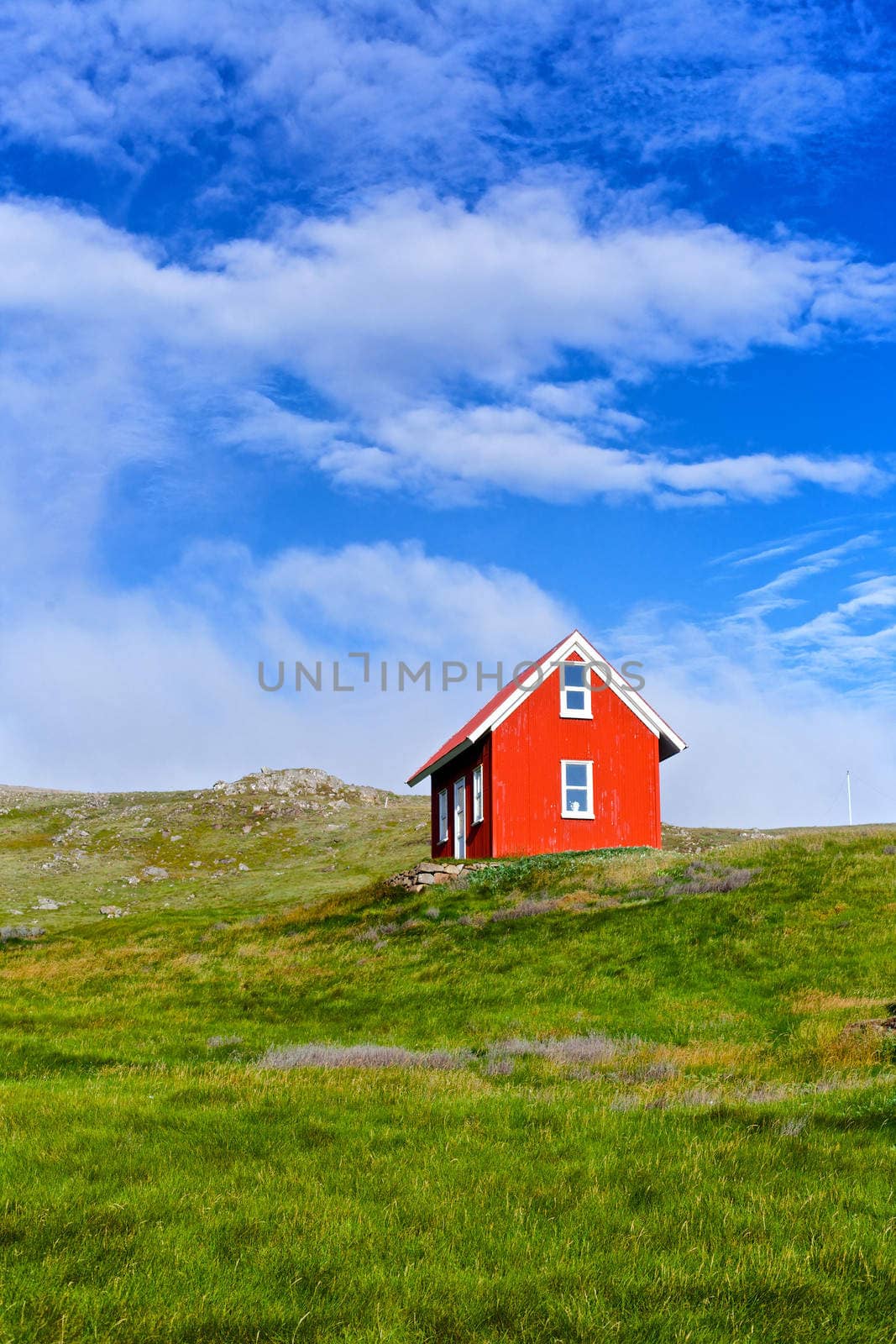 Beautiful red house against the blue sky in Iceland. Vertical view