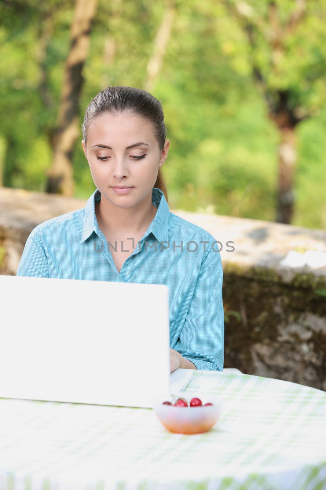 Beautiful girl working on laptop in a summer day
