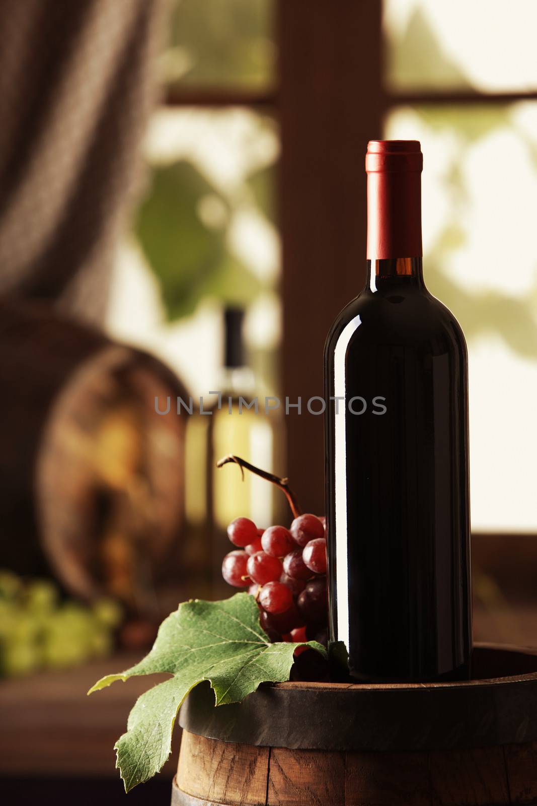 Red Wine bottle and grapes on wooden barrel