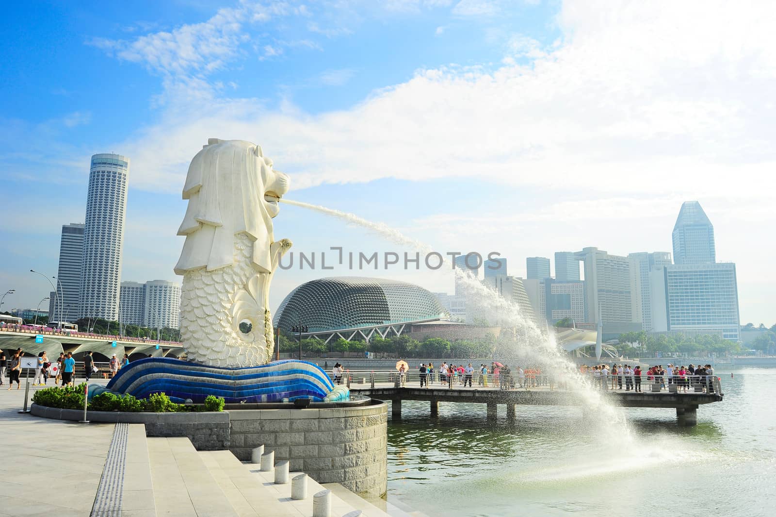Singapore, Republic of Singapore - May 08, 2013: Tourists at the Merlion fountain in front of Esplanade Theatres on the Bay in Singapore. Merlion is a imaginary creature with the head of a lion, seen as a symbol of Singapore