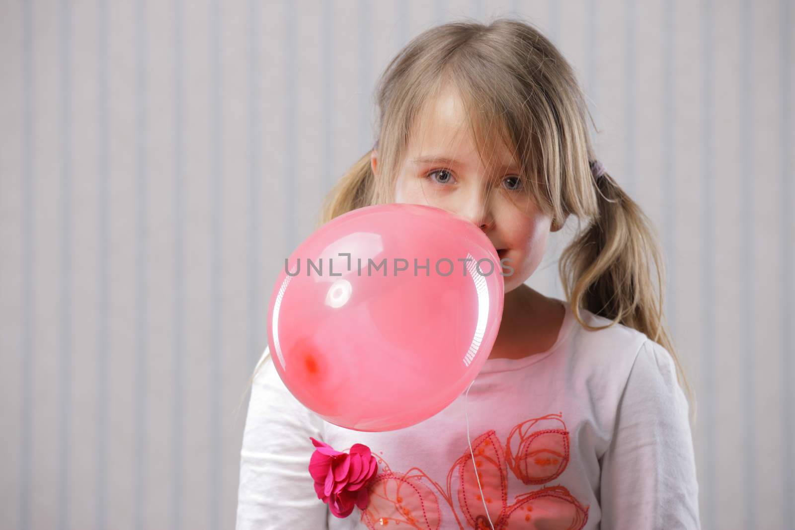 Portrait of a little beautiful girl with a pink balloon