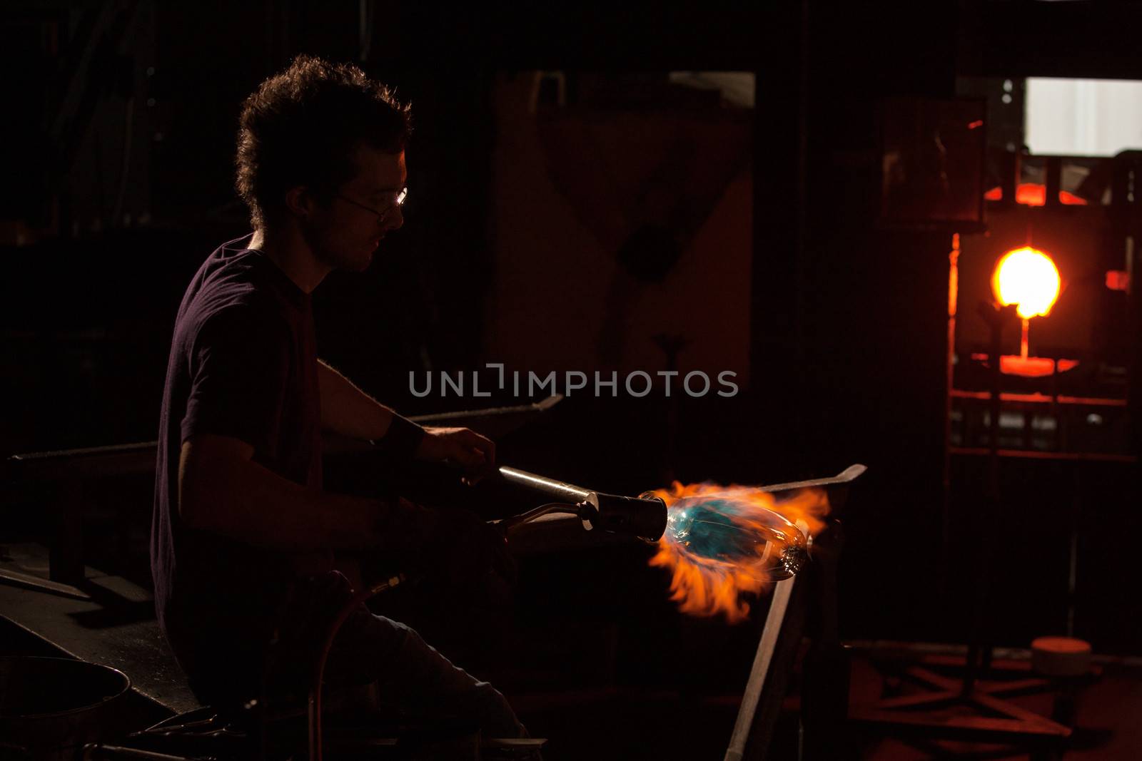 Hot flame from blowtorch shaping a glass object
