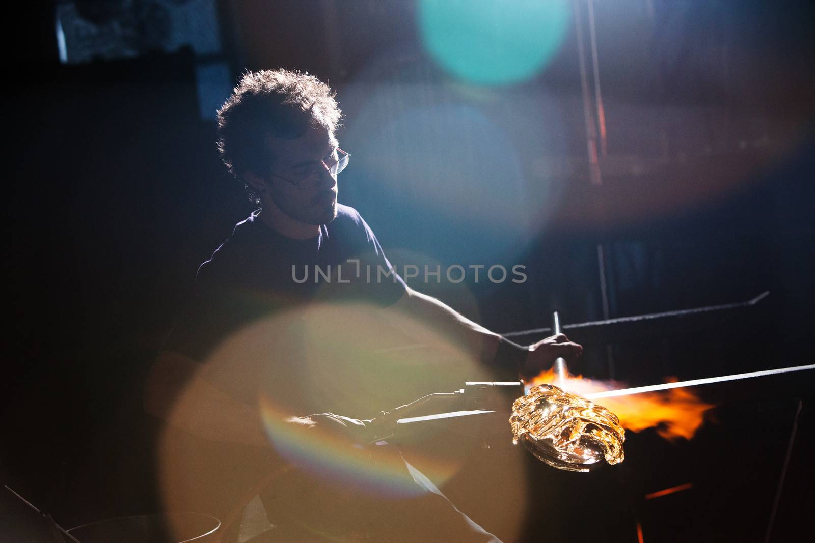 Lens flares surround glass worker creating vase