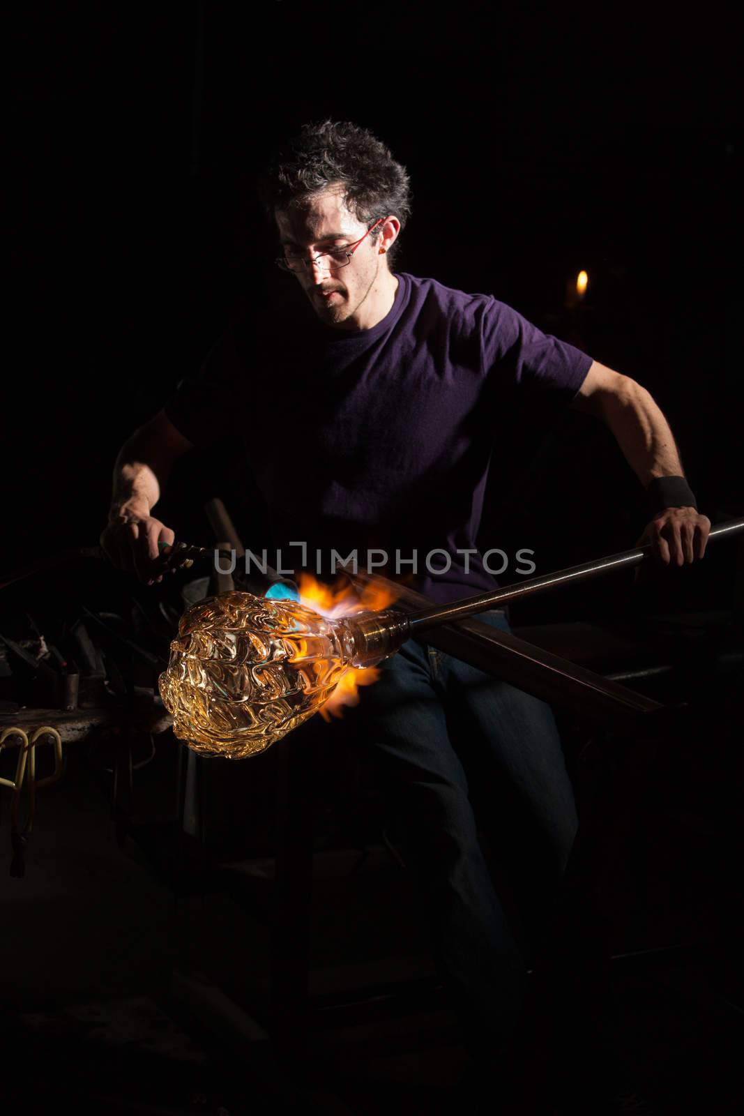 Glass craftsman using blowtorch to shape a jar