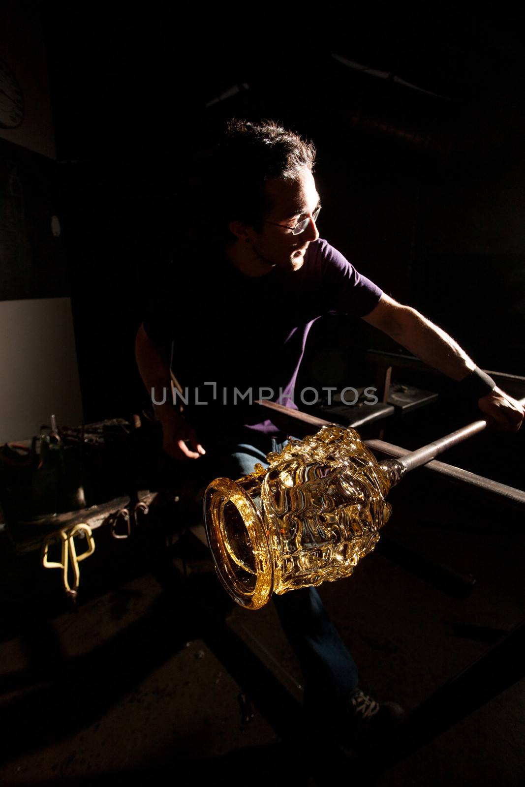 Man finishing fine art glass jar with rod
