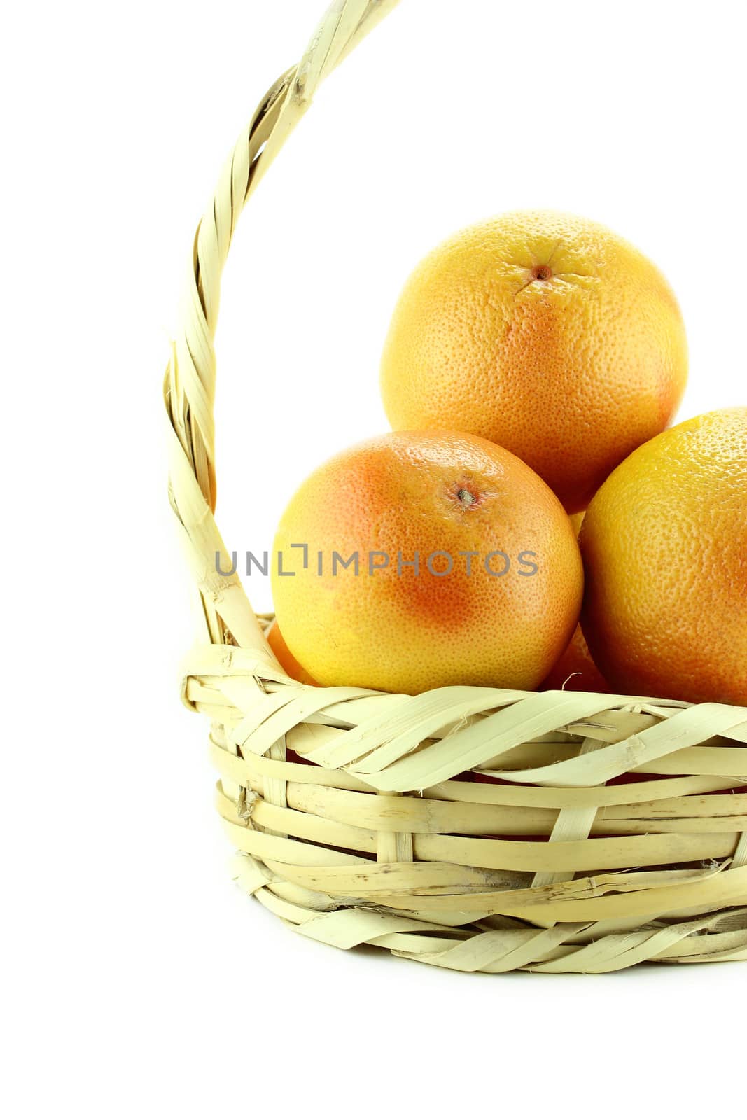 Ripe appetizing grapefruit in straw basket .