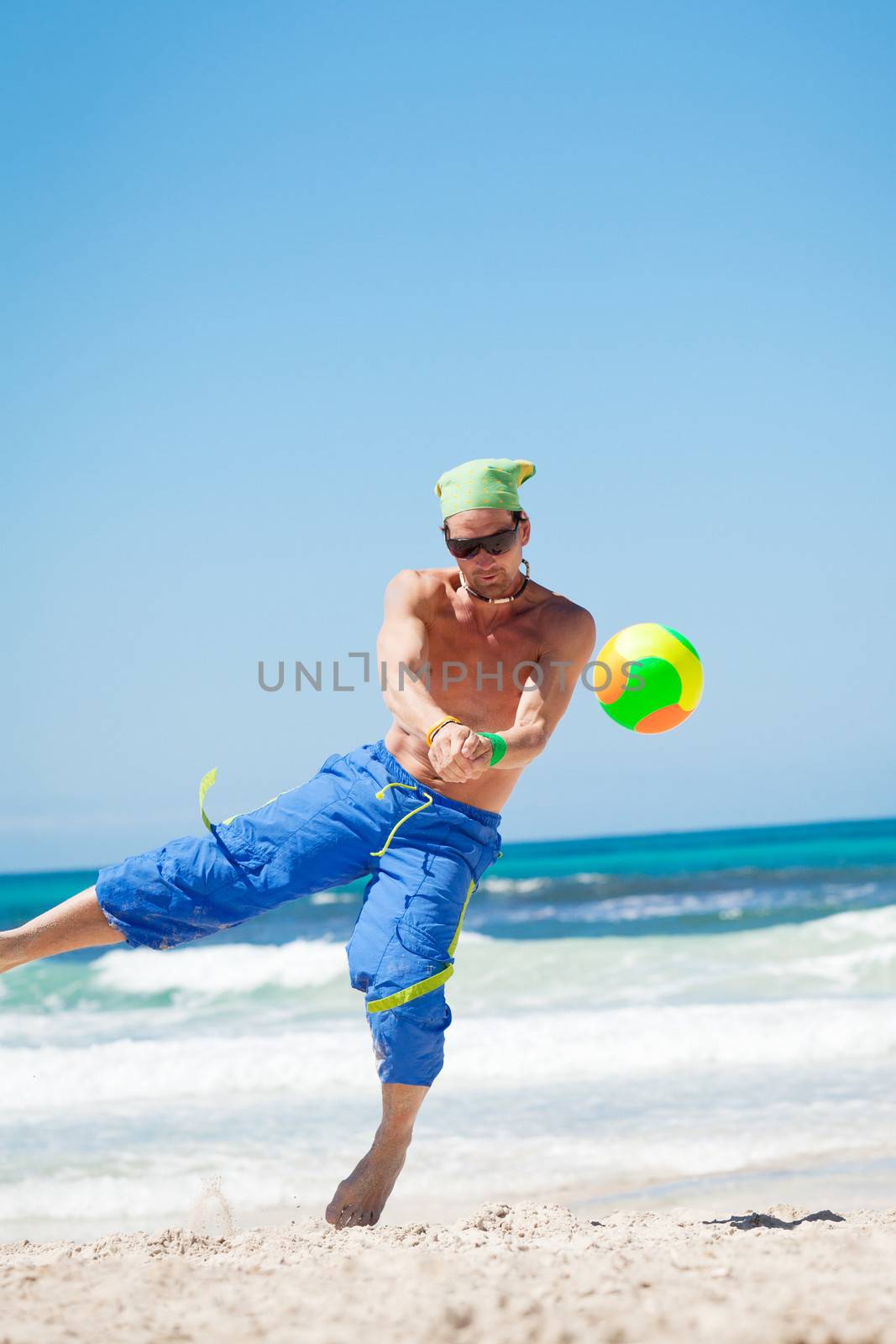 attractive young man playing volleyball on the beach summertime 