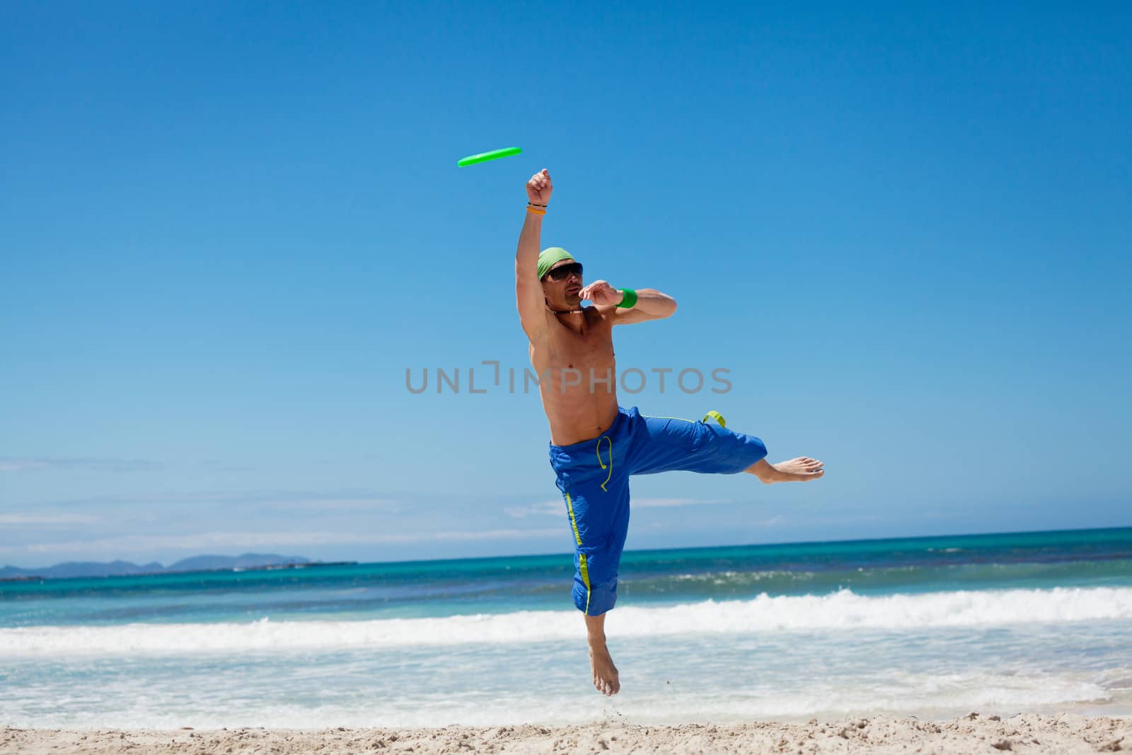 attractive man playing frisby on beach in summer sport fitness jump