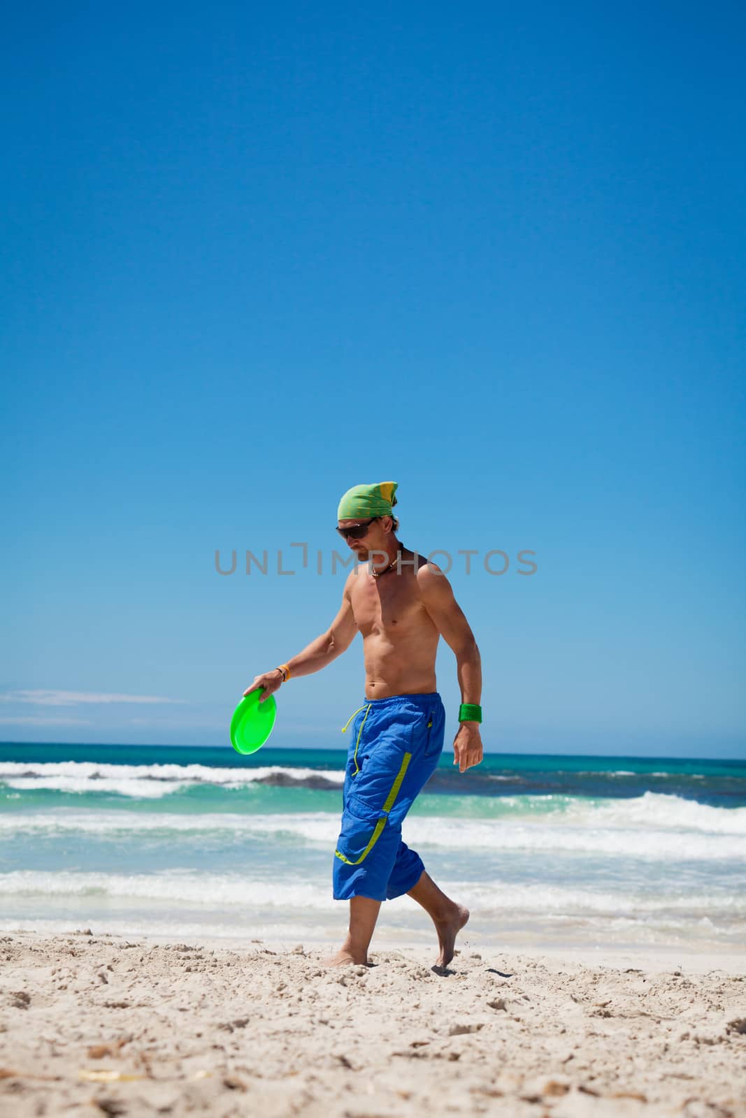 attractive man playing frisby on beach in summer sport fitness jump