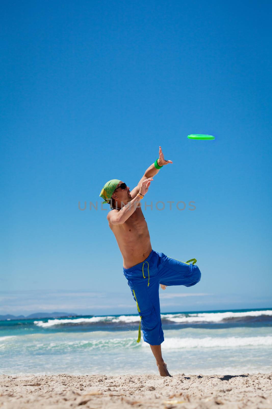 attractive man playing frisby on beach in summer sport fitness jump