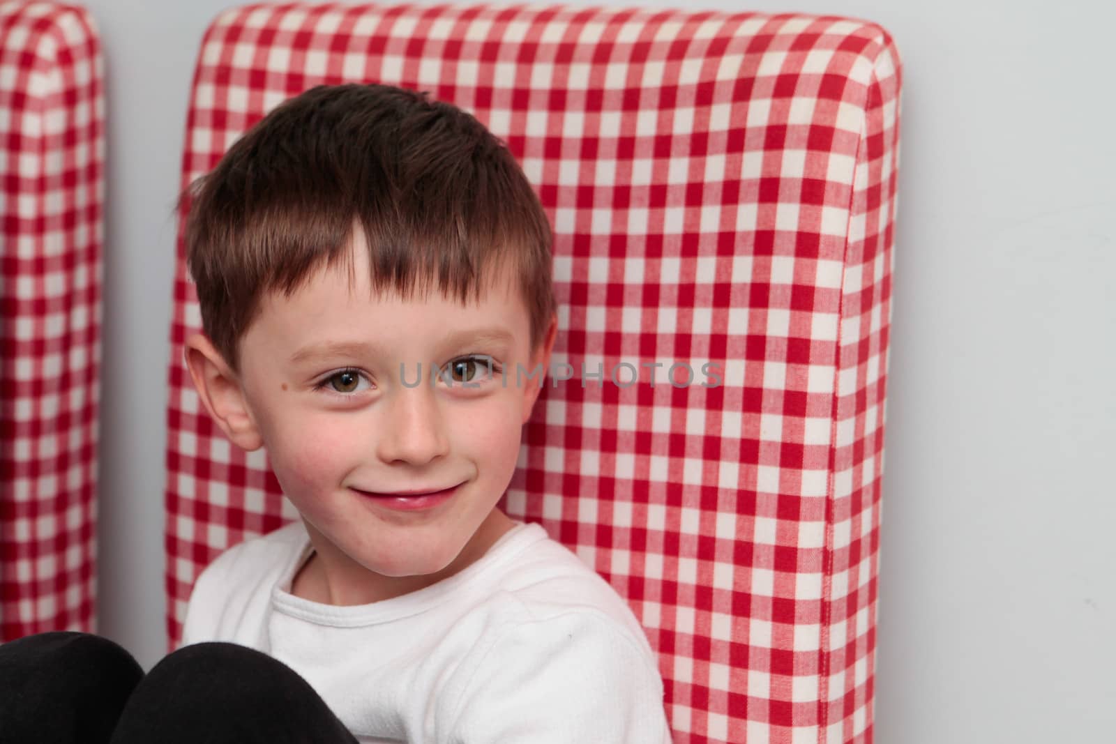 Happy 5 year old boy on a gingham chair