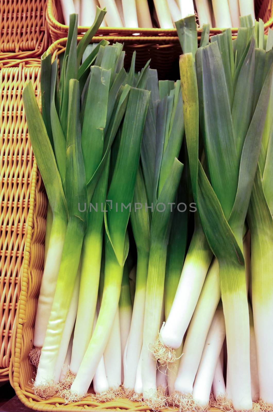 Group of whole leek onions in a basket at marketplace