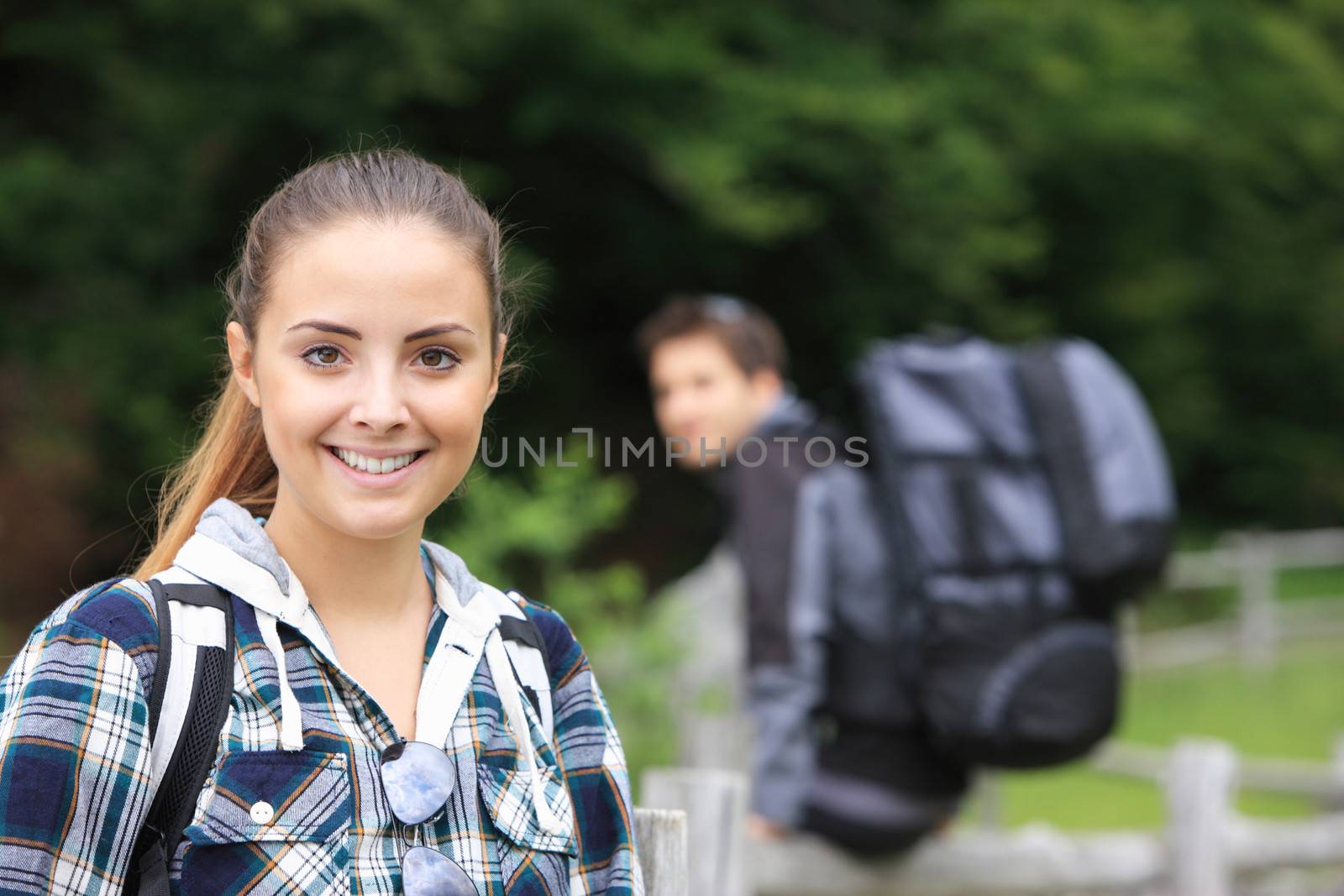 Portrait of young smiling woman hiker, her boyfriend on background