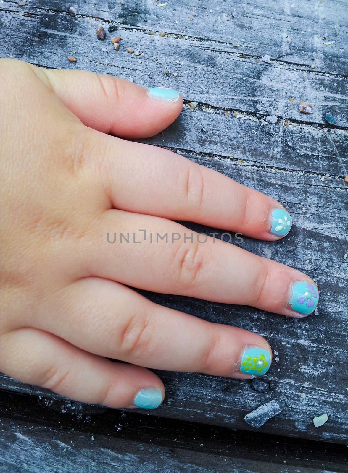 Child with flower paint manicure, towards old wood