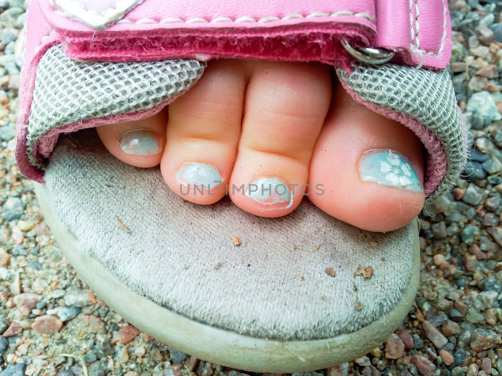 Beautiful blue pedicure on a child's foot in a sandel