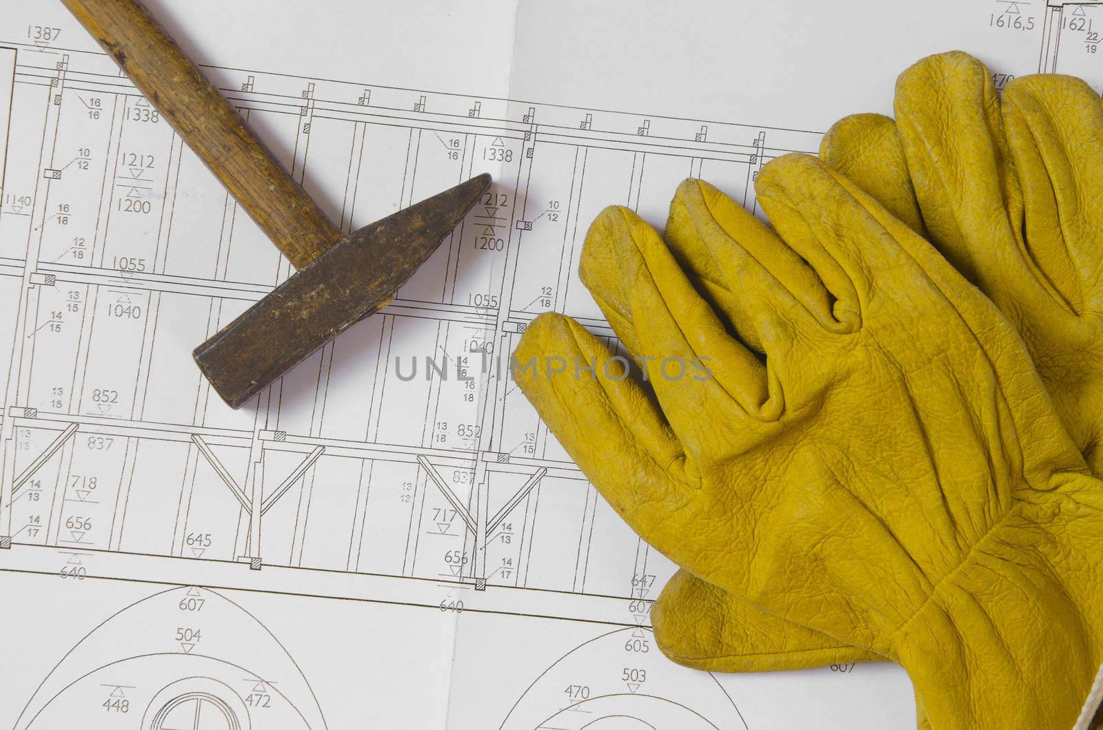 building plans with hammer and working gloves on top