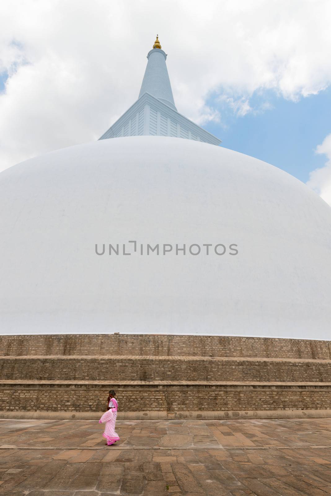 Woman in sari go round 103 m high white sacred stupa Ruwanmalisaya dagoba on Apr 16, 2013 in Anuradhapura, Sri Lanka