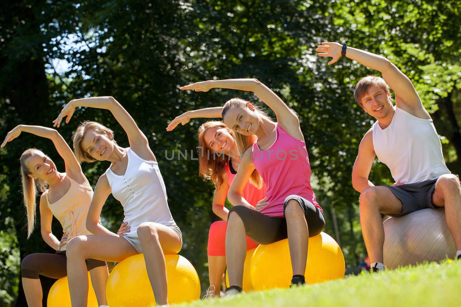 Young caucasians working out in a park with the fitness balls