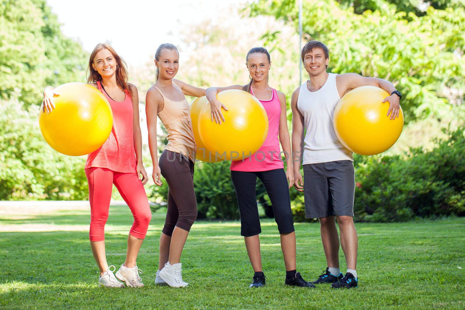 Young caucasians working out in a park with fitness balls
