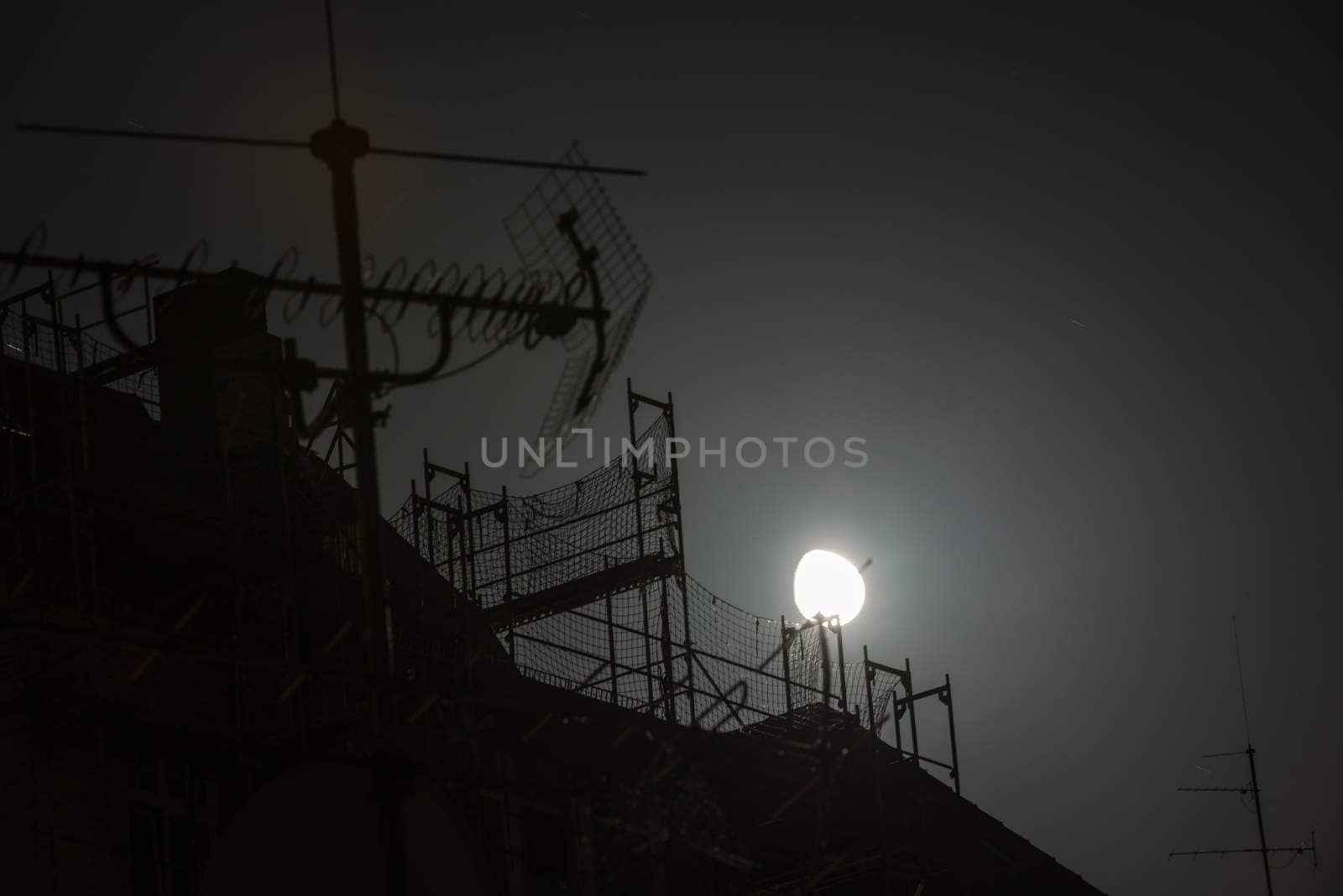Full moon over the roofs of housed and a scaffolding