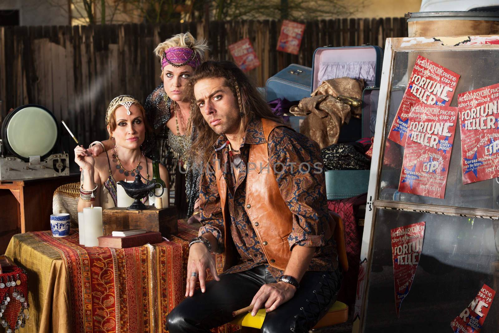 Three serious fortune tellers sitting outside with table
