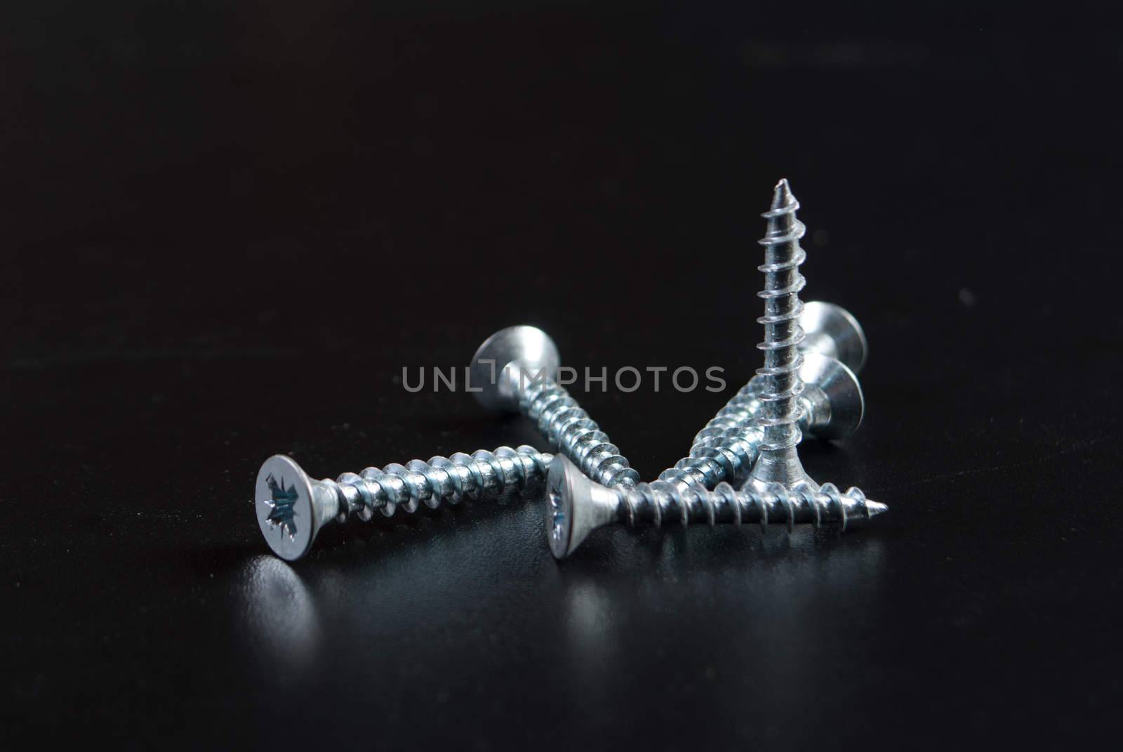 Screws and screwdriver on black background.