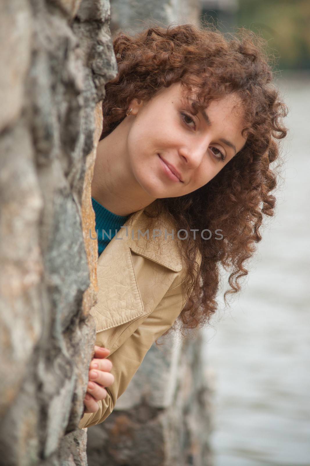 Beautiful sexy brunette girl poses near stone wall