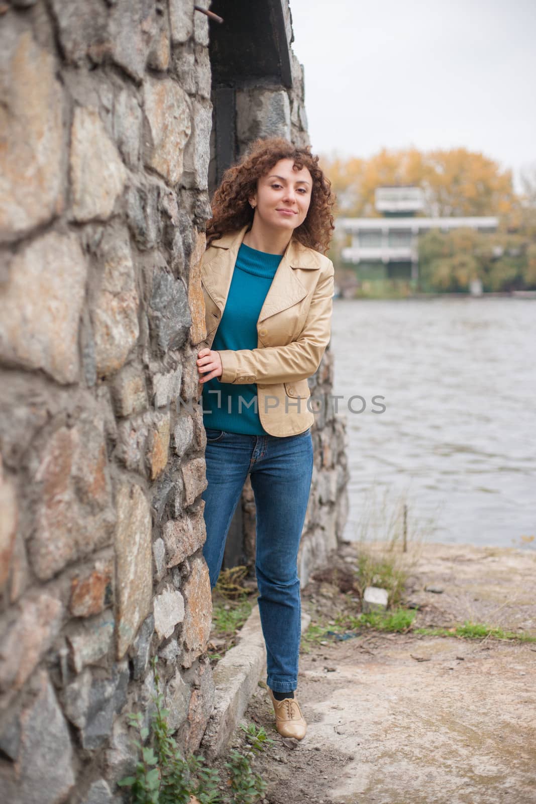 Beautiful sexy brunette girl poses near stone wall