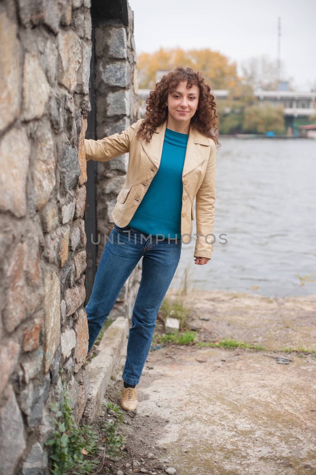 Beautiful sexy brunette girl poses near stone wall