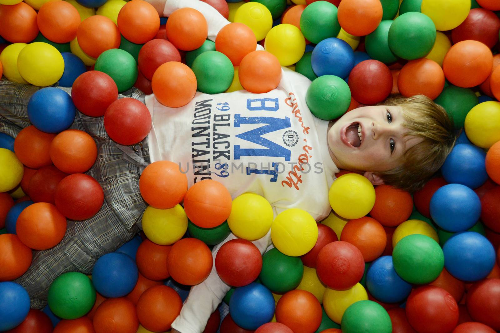 little happy kid playing with colored balls
