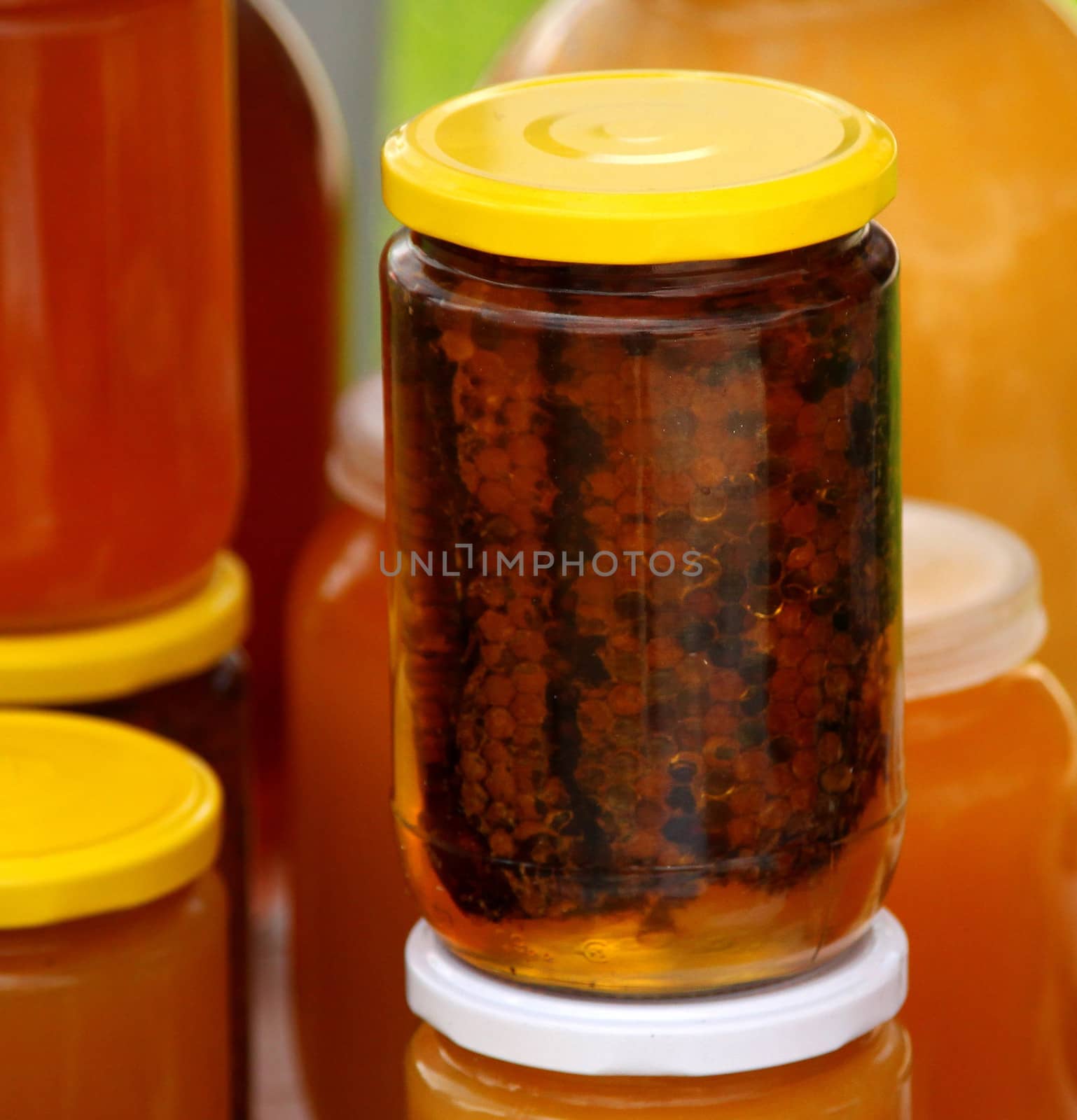 A honeycomb and a honey in a glass jar by indigolotos