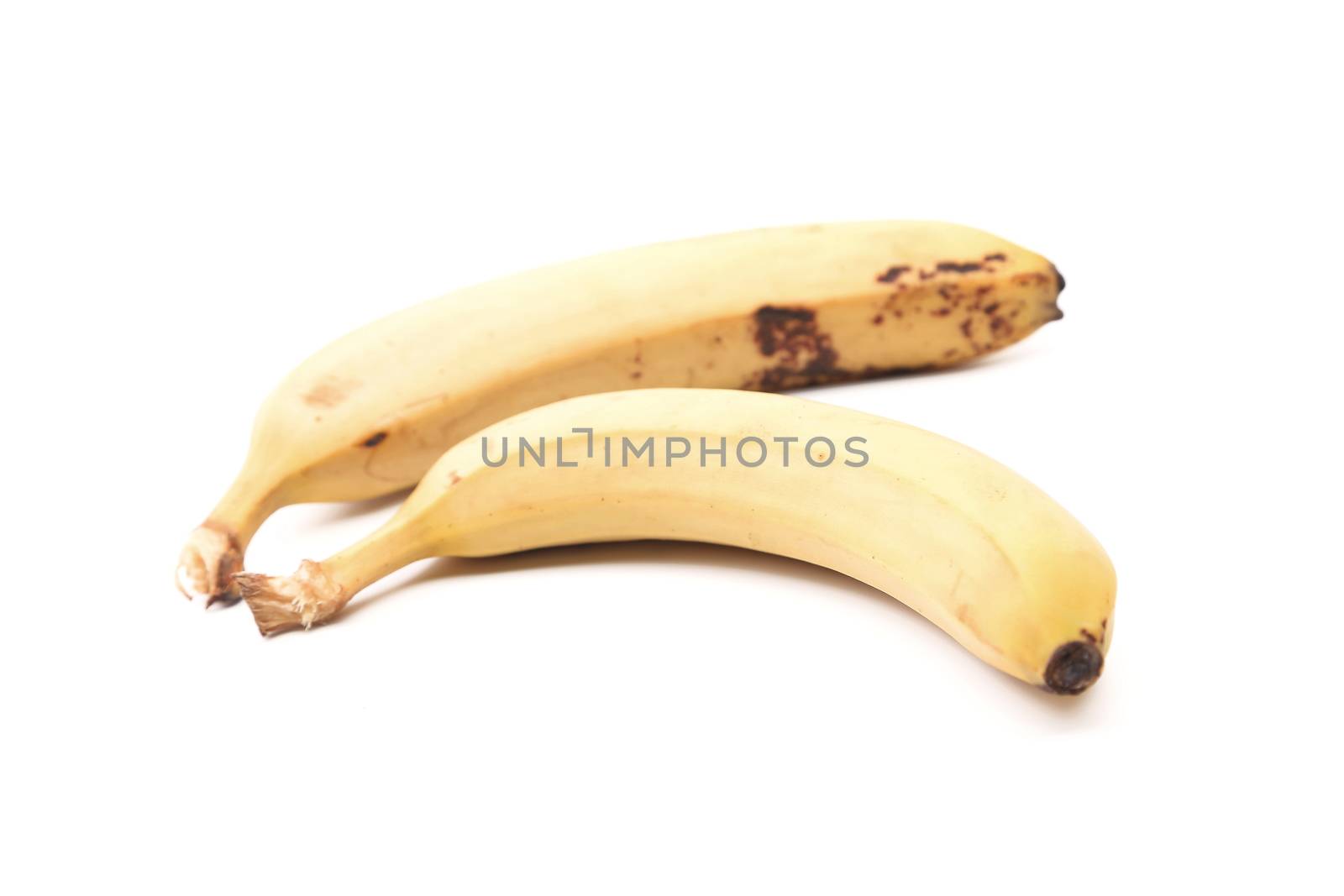 Detail of two old speckled bananas on a white background