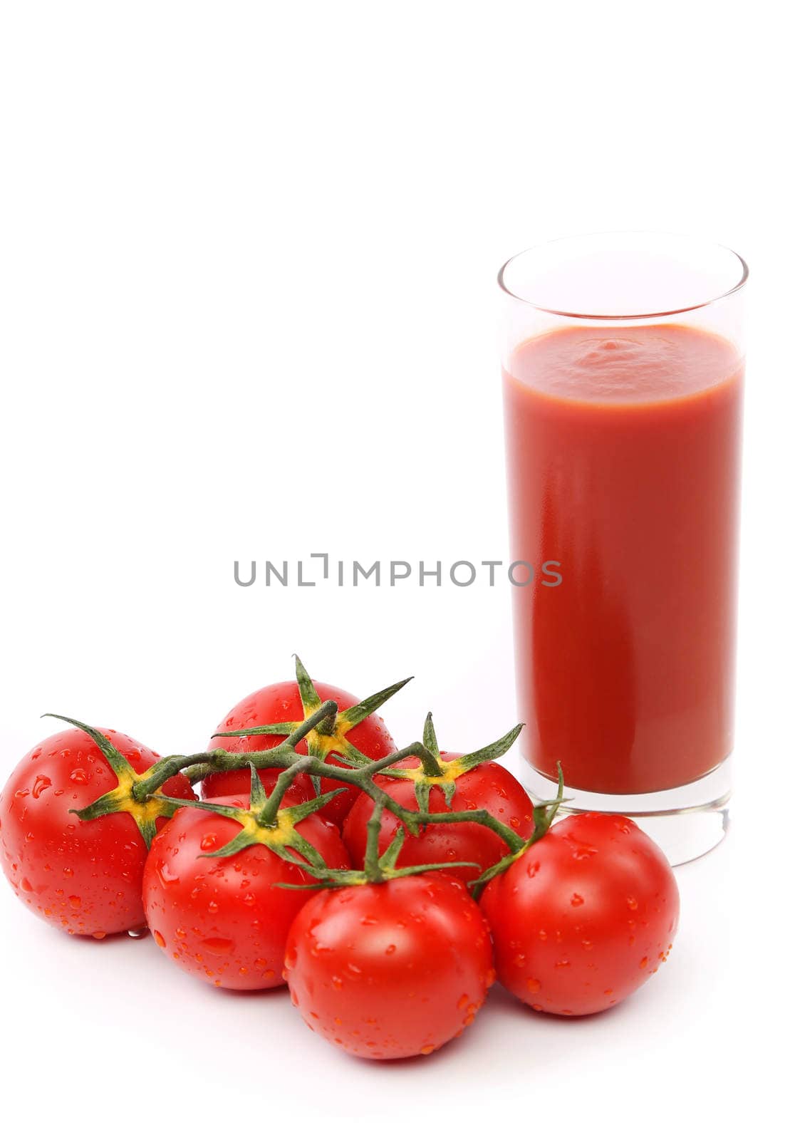 Tomato juice in glass with a cluster of tomatoes isolated on white background