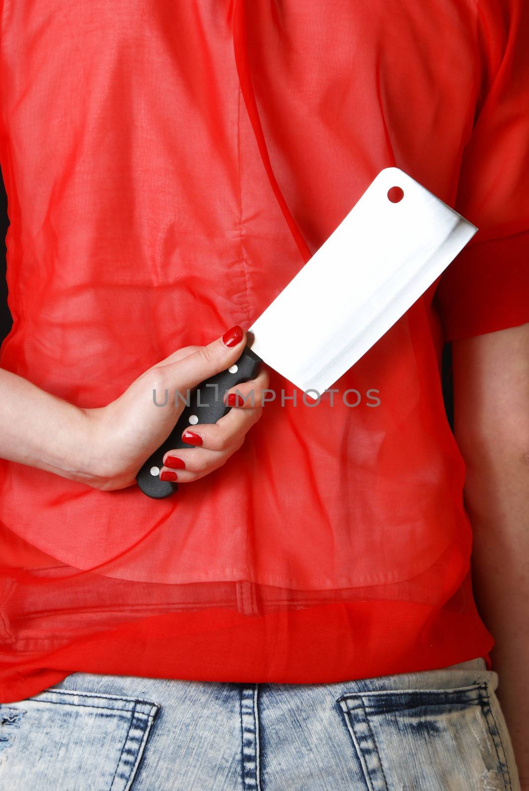 A young housewife conceals a knife behind her back while in the kitchen.