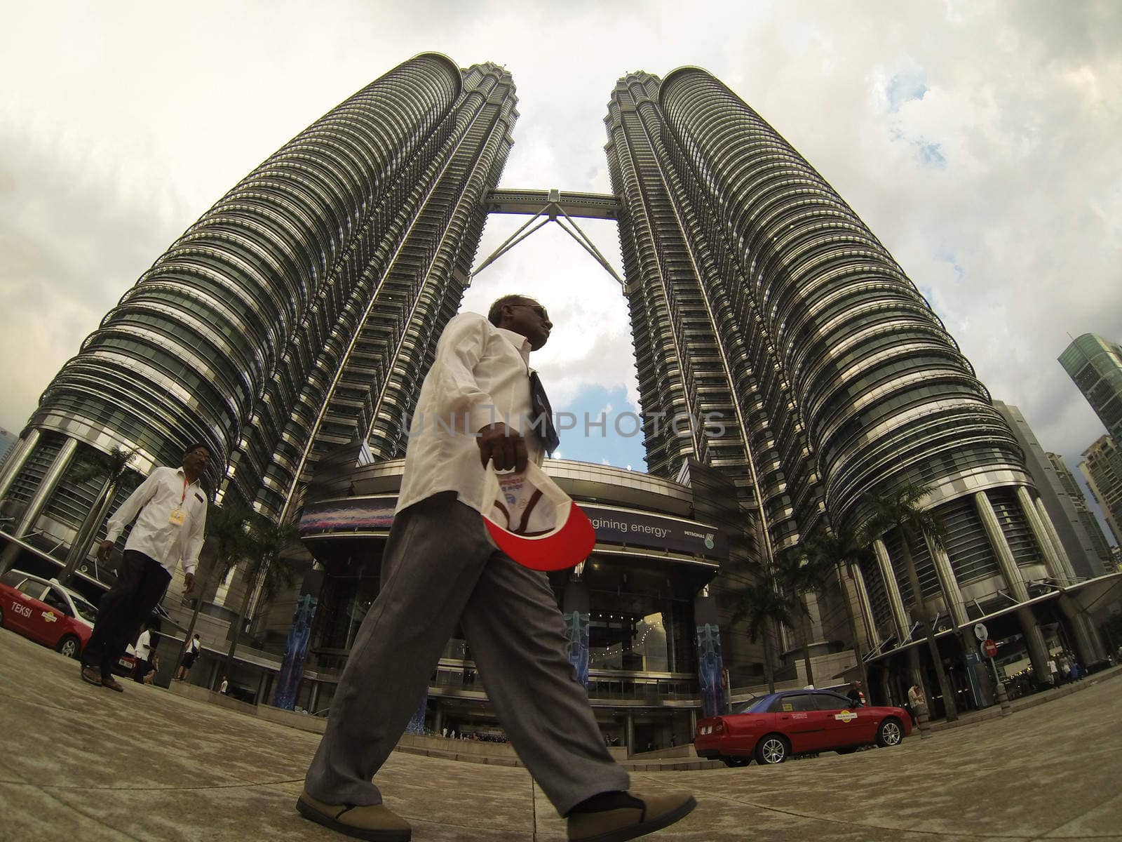 KUALA LUMPUR - MARCH  02:  man passing in front of Petronas Towers  at night  on March  2, 2013 in Kuala Lumpur, Malaysia