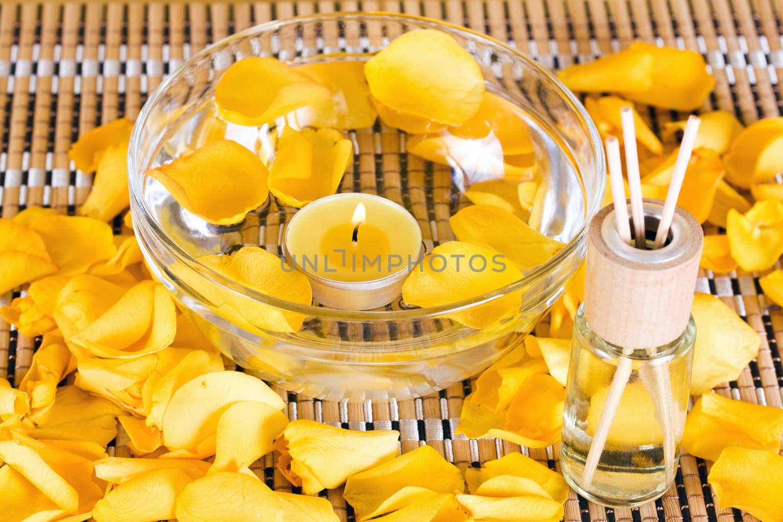 Essential oil with rose petals on wooden background