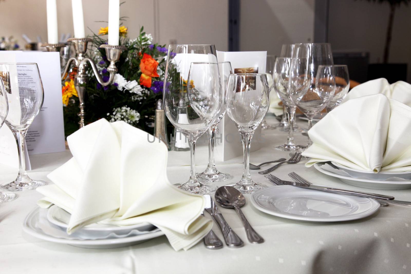Stylish white table setting with elegant glassware, silverware and a floral centrepiece at a wedding reception