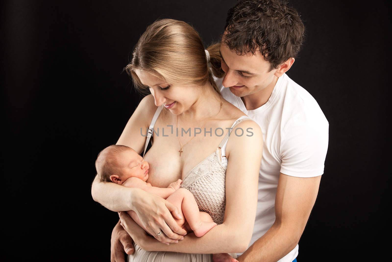 Young caucasian couple with one week old boy over black