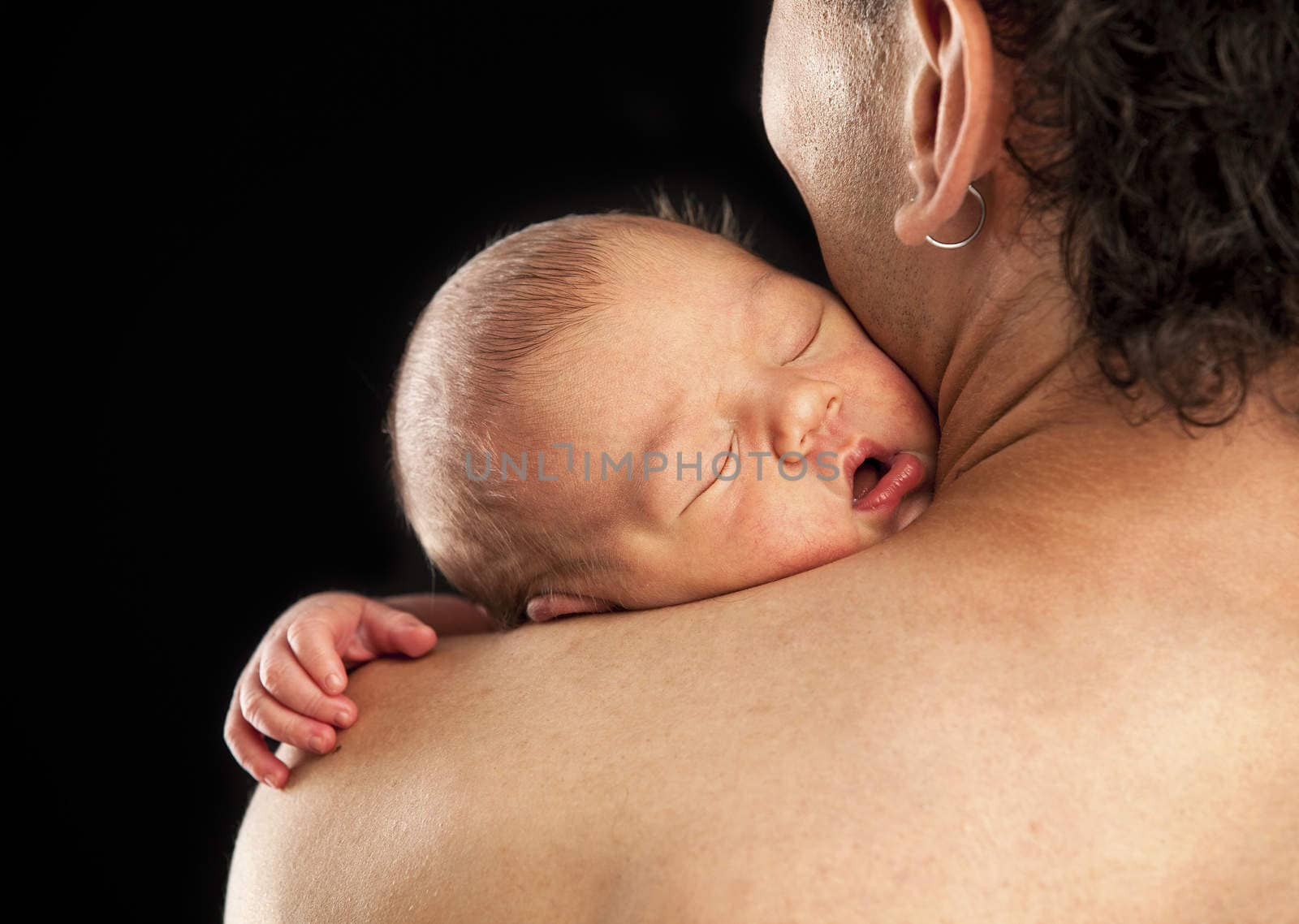 Newborn boy sleeping on his dad's shoulder over black