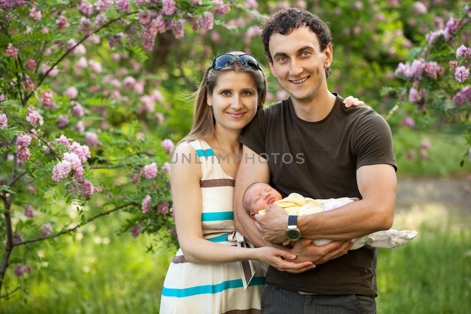 Young couple with newborn son outdoors in spring by photobac