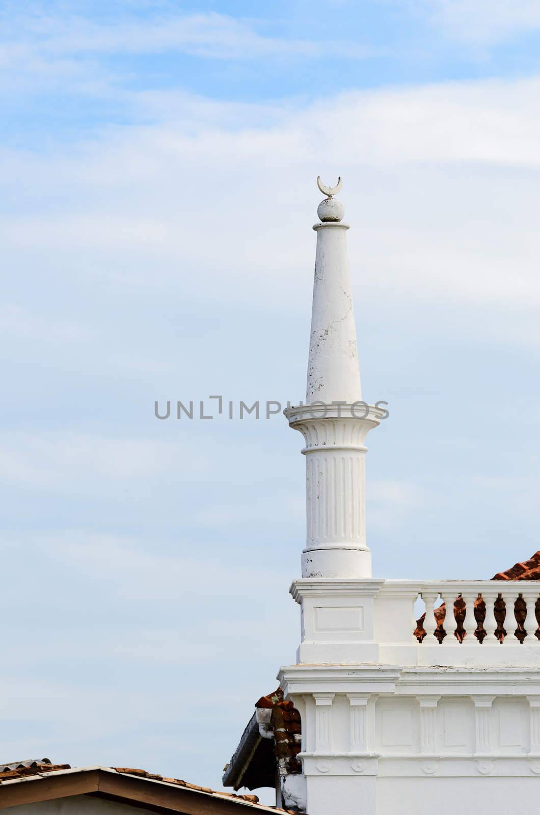 White  mosque column with muslim Crescent above tiled roofs, Galle, Sri Lanka