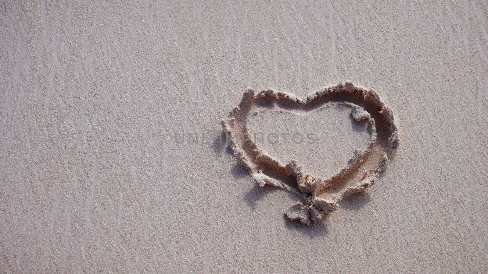Symbol of love drawn in sand on the coast