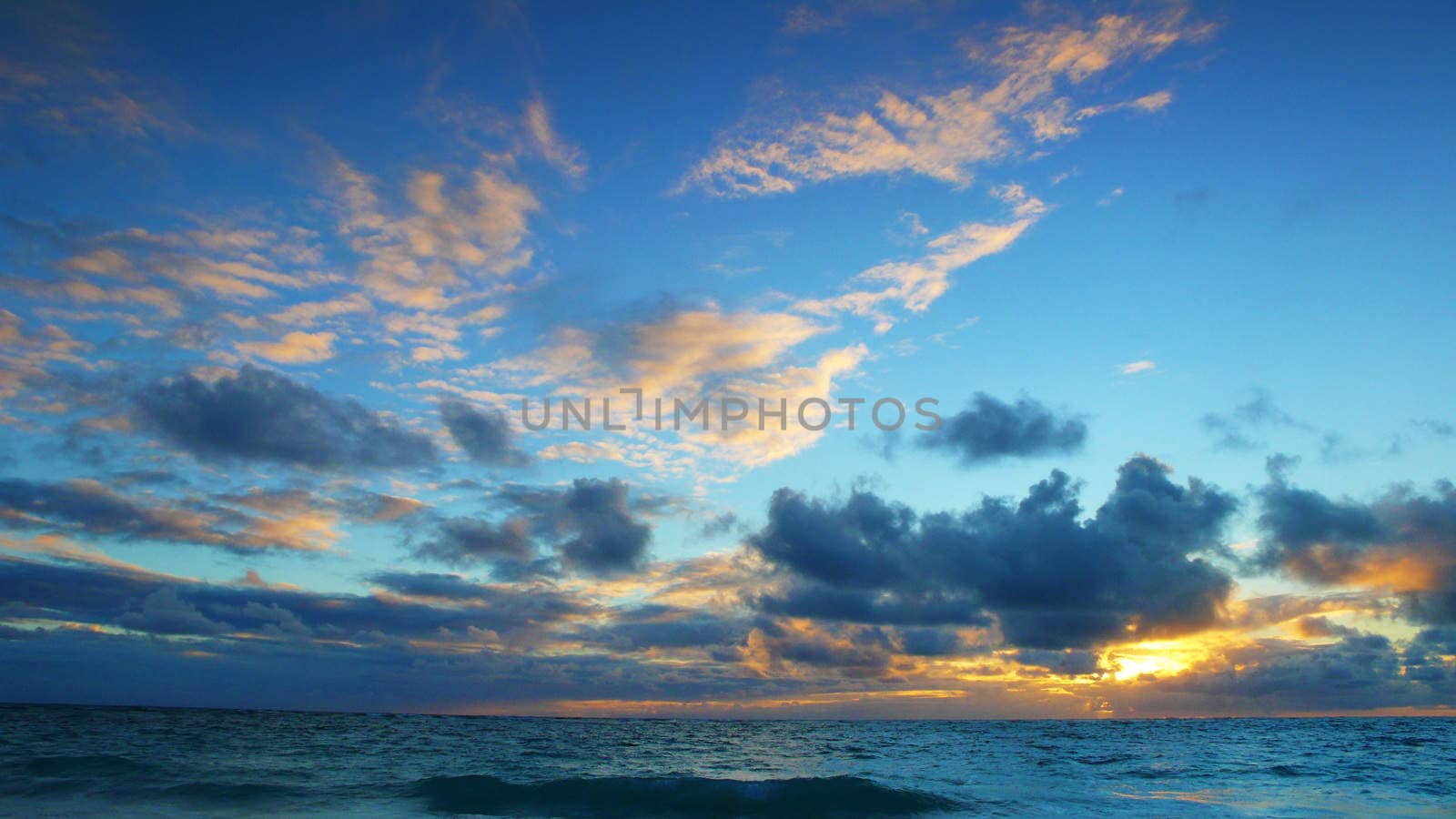 Wavy sea horizon with cloudy blue sky