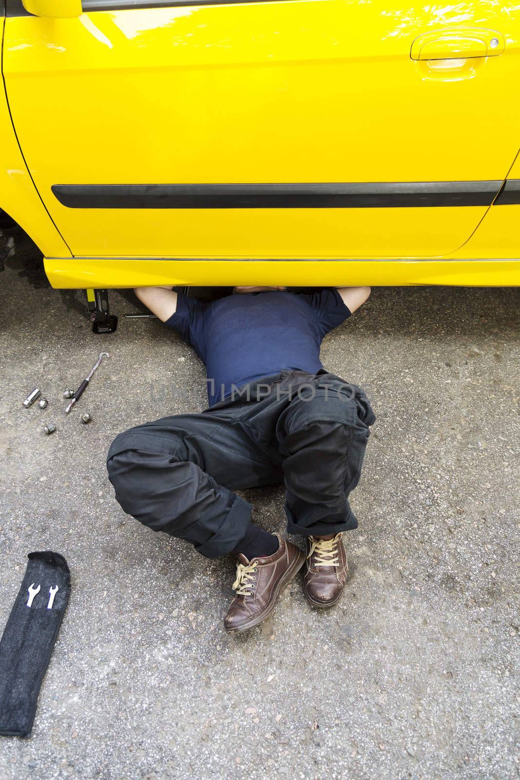 A mechanic underneath a car doing regular maintaince job. 