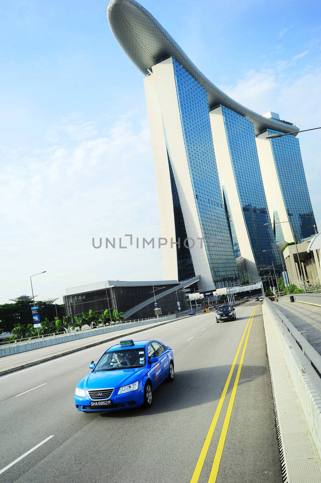 Singapoer, Republic of Singapore - May 09, 2013: Taxi cab driving by the road in front of Marina Bay Sands hotel in Singapore. The government will spend SGP$14 billion to improve Singapore's road infrastructure