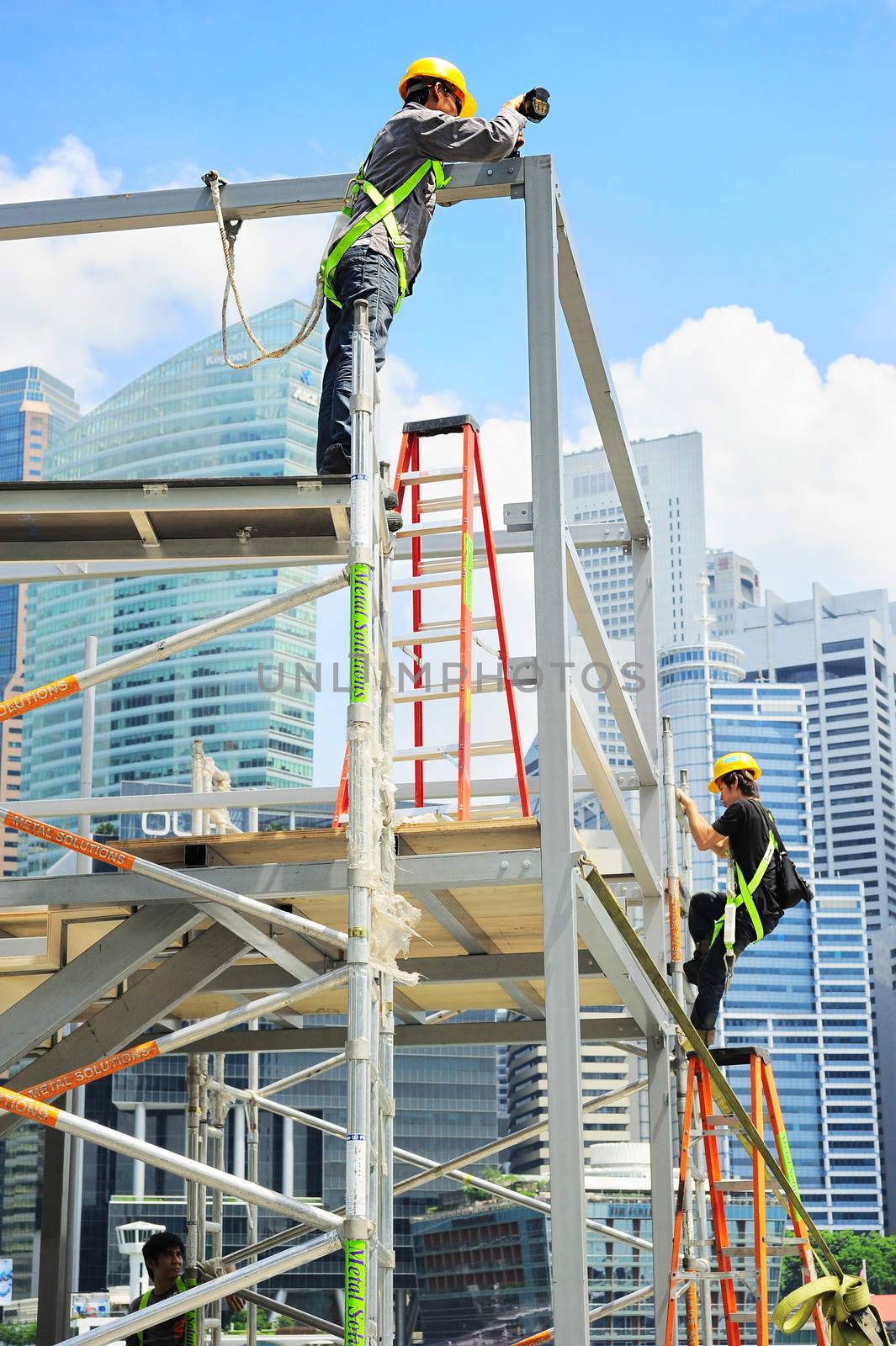 Singapore, Republic of Singapore - May 09, 2013: Workers at construction site in front of Singapore downtown. Construction industry is expected to pull in some S$30 billion this year
