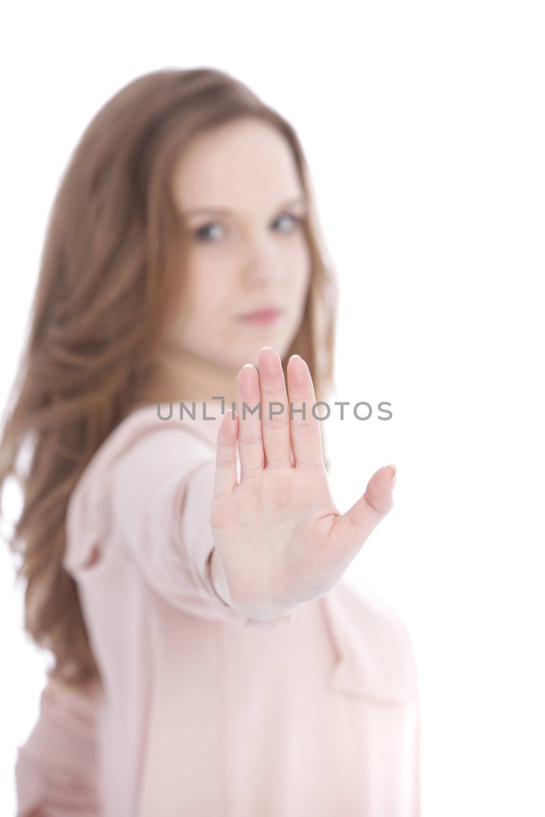 Young woman with a stern expression giving a Stop gesture with her hand holding up the palm facing the camera to indicate she has had enough